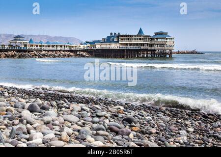 The pier and well known ' La Rosa Nautica' restaurant are seen from the pebble beach. Stock Photo