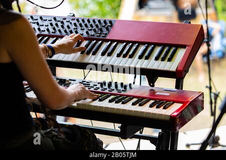 A close up selective focus shot on the hands of a woman playing two electronic keyboards on stage during a festival celebrating acoustic sounds Stock Photo