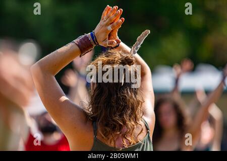 A selective focus shot on a woman practicing mindful yoga, in a standing asana with raised arms during a festival celebrating nature and mindfulness Stock Photo