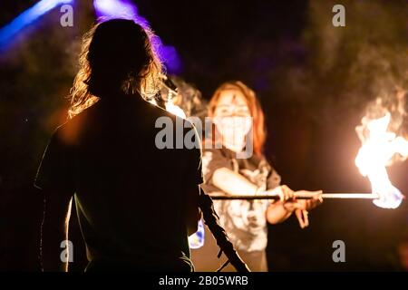 A selective focus shot of fire performers using a burning lance by night at a festival celebrating artisans, earth and alternative communities Stock Photo