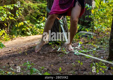 A close up shot on the legs of a woman wearing traditional clothes during an acrobatic slackline performance at a multicultural festival in nature Stock Photo