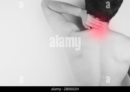 Black and white closeup man suffering from neck and shoulder pain with red spot. Health care and medical concept. Stock Photo