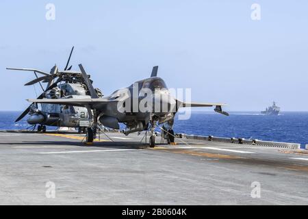 200215-N-BT681-1106 PHILIPPINE SEA (Feb. 15, 2020) An F-35B Lightning II and a CH-53E Super Stallion assigned to Marine Medium Tiltrotor Squadron (VMM) 265 (Reinforced) are secured to the flight deck of amphibious assault ship USS America (LHA 6) as the ship conducts an exercise with amphibious transport dock ship US Germantown (LSD 42). Operating as an Expeditionary Strike Force, the Navy-Marine Corps team integrates  the combat power of the Theodore Roosevelt Carrier Strike Group with the flexible capability of the America Expeditionary Strike Group to provide the fleet commander with a capa Stock Photo