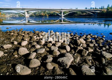 Receding Water under Bridge with Smooth Rocks by a River in California Stock Photo