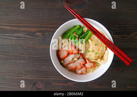 Top View of Roasted Pork Wonton and Egg Noodle Soup Served on Wooden Table Stock Photo