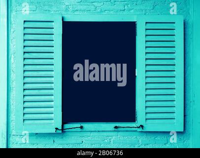 Ice blue colored wooden window with shutters on brick wall Stock Photo