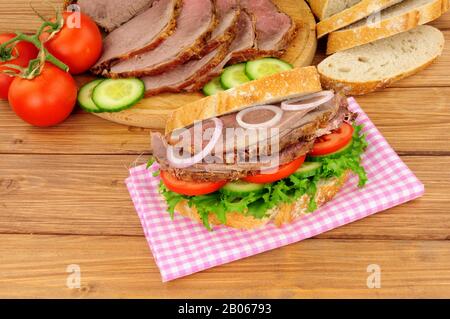 Roast beef salad sandwich with ingredients on a wood background Stock Photo