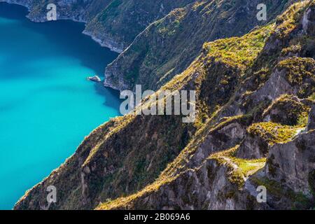 Cliffs with vegetation in the Andes mountains and the magic turquoise waters of the Quilotoa crater lake near Quito, Ecuador. Stock Photo