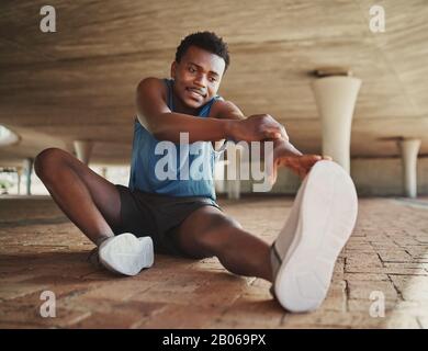 Athletic millennial black man warming up and stretching Stock
