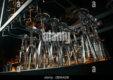 Clean glasses over the bar. Clean glasses for alcoholic beverages hang in several rows over the bar Stock Photo
