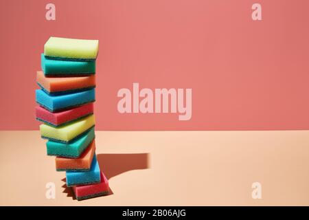 Cleaning equipment, Kitchen sponges. A stack of multi-colored sponges for dishes on a bright 3D background with childish sunlight and shadow. copyspac Stock Photo
