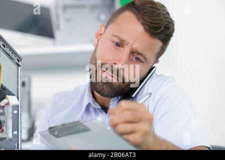 man on the phone writing on clipboard Stock Photo
