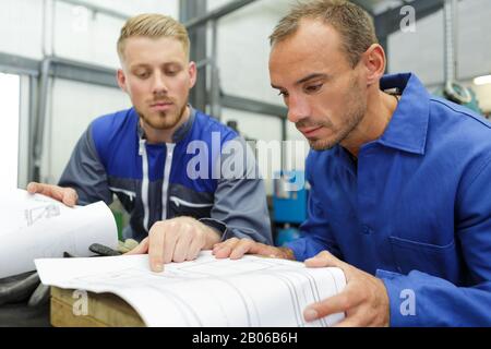 two technicians read a plan in the workshop Stock Photo