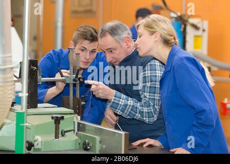 engineer training apprentices on machine Stock Photo