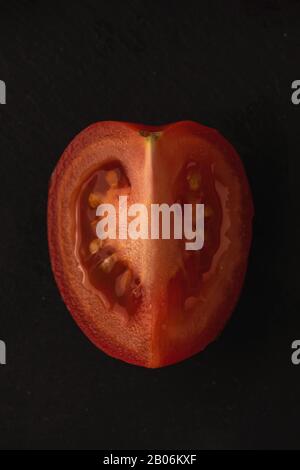 one slice of ripe tomato on black background. Stock Photo
