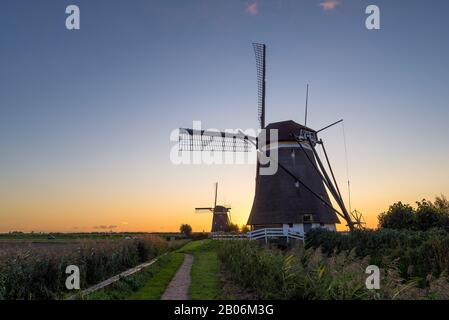 Traditional dutch windmills in a row with beautiful evening sky Stock Photo