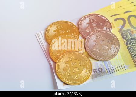 Golden bitcoin coins on the background of 200 Euro paper notes. The concept of trading and the value of cryptocurrencies and euros . Stock Photo