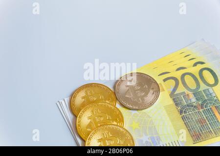 Golden bitcoin coins on the background of 200 Euro paper notes. The concept of trading and the value of cryptocurrencies and euros . Stock Photo