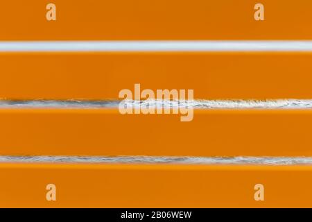 orange horizontal wooden boards, wooden boards between which the waves of the sea are visible. background Stock Photo