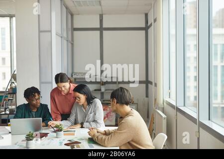 Young business people sitting at the table and planning new project together during work day at office Stock Photo