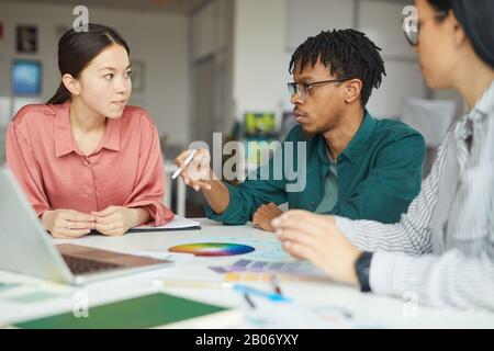 Multiethnic group of business people discussing together at the table during business meeting at office Stock Photo