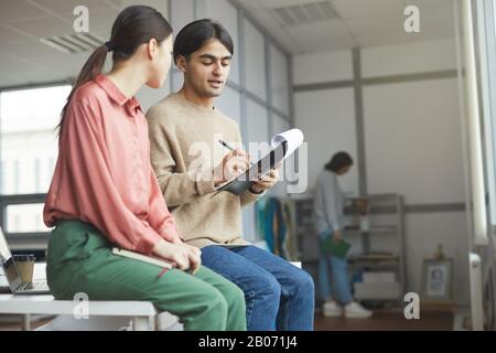 Young business couple sitting on the table and making notes in document they making business plan in team Stock Photo