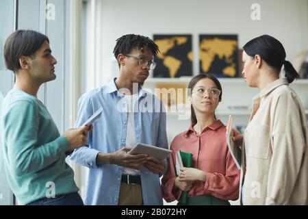 Multiethnic young people standing and talking to each other at office Stock Photo