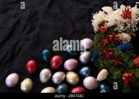 Colored chicken and quail eggs of pink, silver, golden and blue color on black Stock Photo