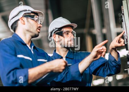 engineer teamwork checking control panel and teaching new worker to operating control the machine in factory. Stock Photo