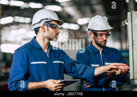 engineer teamwork checking control panel and teaching new worker to operating control the machine in factory. Stock Photo