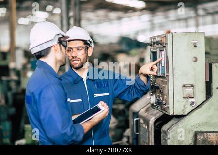 engineer teamwork checking control panel and teaching new worker to operating control the machine in factory. Stock Photo