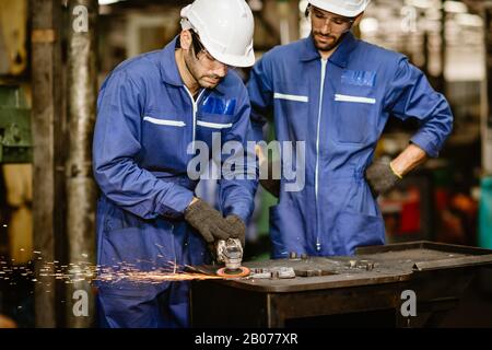 senior worker training and watch new young trainee man to using tool for safety in steel cut ndustrial work. Stock Photo