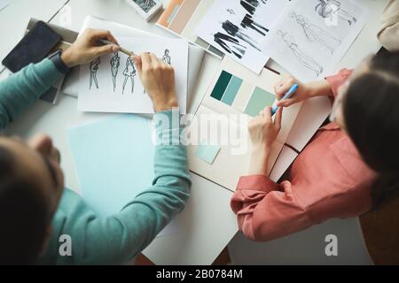 High angle view of two designers working with fashion sketches of clothes and discussing it together during a meeting Stock Photo