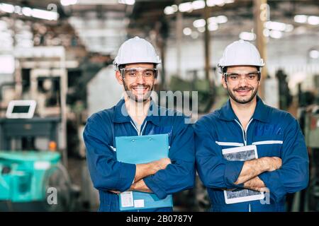Portrait of Happy Engineer team smiling worker working together in industry factory. Stock Photo