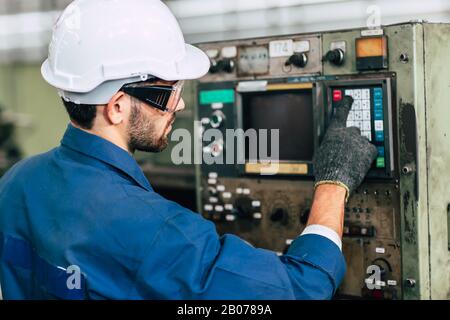 factory worker man operate the machine, high skill labor work industry with safety clothes. Stock Photo