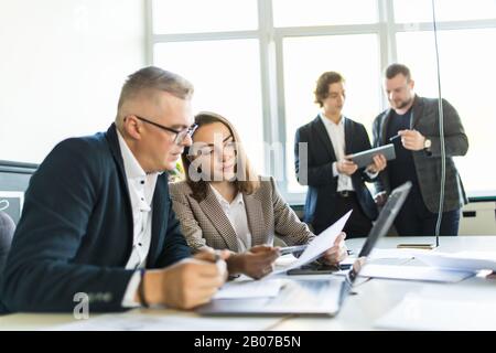 Colleagues talking at work in an informal meeting area Stock Photo