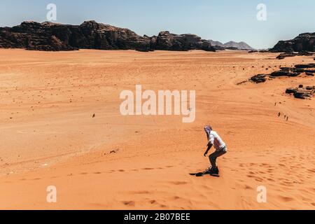 Man sandboarding in Wadi Rum desert, Jordan Stock Photo