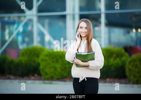 Businesswoman talking on mobile phone in Lviv cityscape background Stock Photo