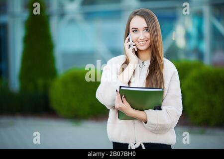 Businesswoman talking on mobile phone in Lviv cityscape background Stock Photo