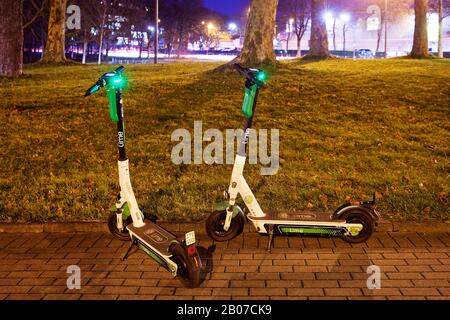 electric scooters on the sidewalk in the evening, Germany, North Rhine-Westphalia, Ruhr Area, Dortmund Stock Photo