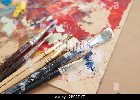 Close-up of different kinds of paintbrushes lying on the table with picture Stock Photo