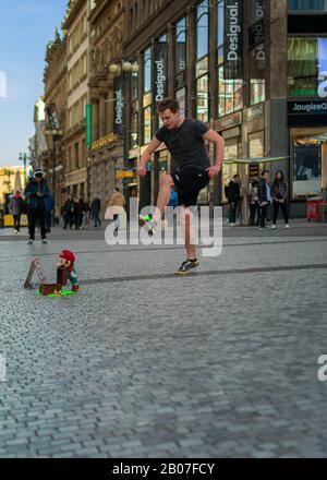 Prague - February 9th 2019: A Street Performer does tricks with a green tennis ball in the centre of the city with a crowd of onlookers. Stock Photo