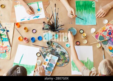 High angle view of group of children painting their pictures with watercolor paints during art lesson