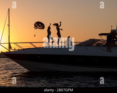 Partygoers dancing in the sunset on a boat moored off the shore by Cafe Mambo in the party capital of San Antonio on the Island of Ibiza Stock Photo