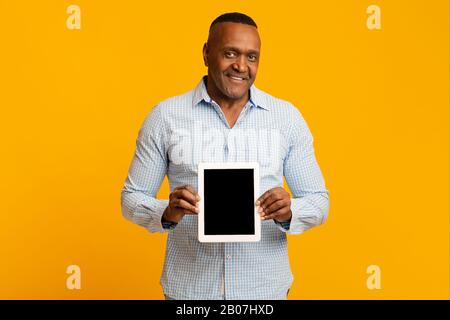 Smiling middle aged african man showing blank digital tablet Stock Photo