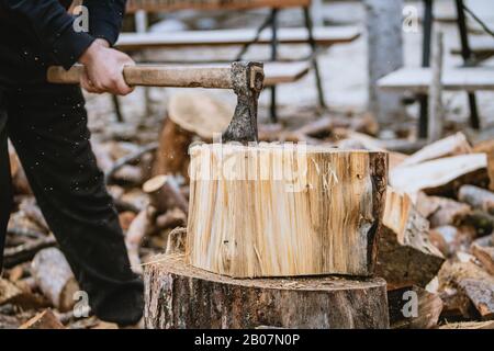 Man is chopping wood with vintage axe. Detail of flying pieces of wood on log with sawdust. Stock Photo