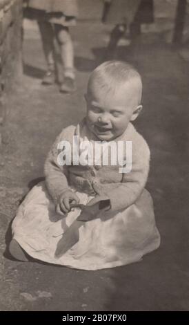 A baby playing in the dirt in a working class district back alley circa 1950 Stock Photo