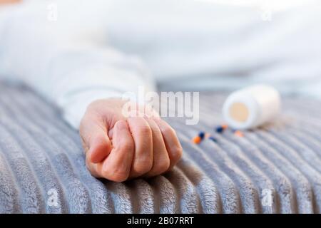 Woman’s hand close up committing suicide by overdosing on medication, pills and bottle beside. Overdose pills and addict concept background Stock Photo