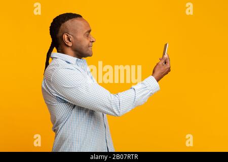 Middle aged afro man scanning his face on cellphone Stock Photo