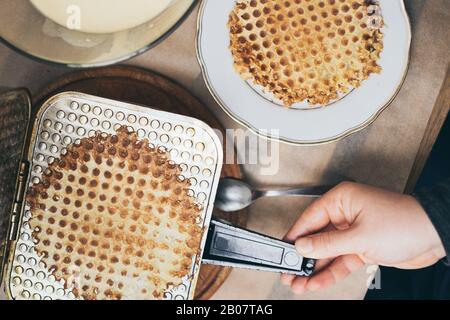 Close up on female hands cooking homemade waffles on vintage waffle-iron Stock Photo